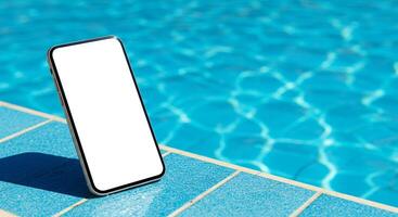 A smartphone is sitting on a pool edge with a blank screen photo