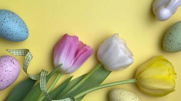 Easter eggs and tulips move slightly on a yellow background video