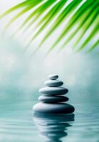 Stacked stones in balance with palm leaf and blue vertical background creating zen-like atmosphere. . photo