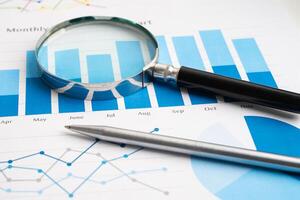 Magnifying glass on spreadsheet and graph paper. Financial development, Banking Account, Statistic photo