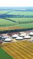 Biogas complex on field in summer. Enterprise for processing organic waste. Organic plant for biogas technologies. Aerial view. Vertical video