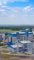 Innovative plant built in nature. Large industrial territory with grain elevators and modern buildings. Dryer silos on field. Panoramic view on factory from the air. Vertical video