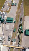 Agricultural silos on field. Grain elevators for storage and drying of cereals. Modern grain-drying complex. Orbital view from above. Vertical video