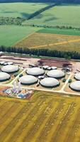 Storage tanks for biomass on fields background. Agricultural and greenhouse complex is equipped with its own biogas. Aerial view. Vertical video