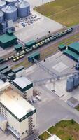 Grain elevators on field. Modern industry for agribusiness. Grain drying complex with large bins. Grain storage tanks. Aerial view. Vertical video