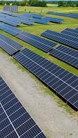 Ecological power station outdoors. Flying over the rows of blue solar panels on the field in summer. New source of electricity. Drone view. Vertical video