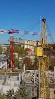 Construction of a new shopping center. Urban background and two cranes on construction site. shooting with drone. Vertical video