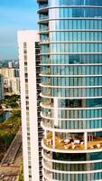 Drone approaching the beautiful high-rise apartment block on the coast of the Atlantic Ocean. Miami Beach architecture on sunny day. Vertical video