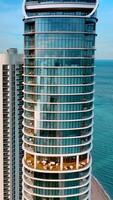 Splendid view of Miami Beach on sunny daytime. Drone flying at the tops of skyscrapers built on the coast of the Atlantic Ocean. Vertical video