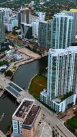 Flying above the diverse cityscape of Miami, Florida, USA. Drone footage of area with high-rise buildings and low-rise architecture at backdrop. Vertical video