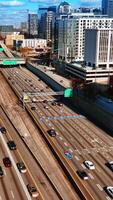 Multiple vehicles going by the busy wide-lane highways in Atlanta downtown. View on the city scenery on sunny day from top. Vertical video