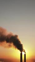 Toxic dark smoke filling the evening sky. Pipes with chemical emissions going into the air against the sunset. Ecological problems in the atmosphere. Vertical video