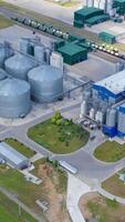 Modern factory at sunlight. Grain drying complex with metal terminals for keeping crop. New granary on field. View from the air. Vertical video