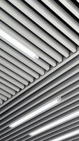 Decoration planks on the ceiling with led lamps for white day illumination. Black and white image. Low angle view. Vertical video