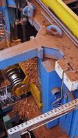 Sawmill. Process of machining logs in a machine different view closeup. Removing bark from logs. Closeup. Vertical video