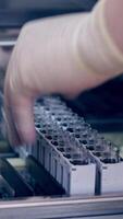 Contemporary equipment in the laboratory. Hands of laboratory worker putting vials into the modern machine in clinic. Modern device for testing blood samples. Vertical video