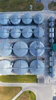 Metal equipment on a modern granary. Silos for keeping crop on field. Modern industrial complex with large grain elevators. Top aerial view. Vertical video