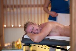 Relaxing Back Massage in a Spa Setting. A professional massage therapist in a blue uniform provides a relaxing back massage to a client lying on a massage table. photo