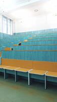 Comfortable classroom without students. Empty auditorium with wooden desks in blue color. Light lecture hall in the University. Vertical video