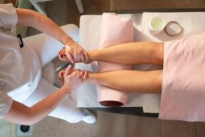 Foot Massage Therapy in a Relaxing Spa Setting. A professional massage therapist in a white uniform provides a soothing foot massage to a client in a calm and serene spa environment photo