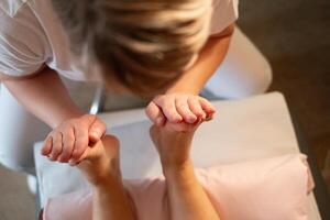 Foot Massage Therapy in a Relaxing Spa Setting. A professional massage therapist in a white uniform provides a soothing foot massage to a client in a calm and serene spa environment photo