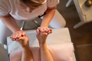Foot Massage Therapy in a Relaxing Spa Setting. A professional massage therapist in a white uniform provides a soothing foot massage to a client in a calm and serene spa environment photo