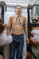 A female doctor performs an ECG on a young man in a hospital room, carefully monitoring his heart health during a routine checkup. photo