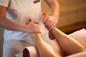 Foot Massage Therapy in a Relaxing Spa Setting. A professional massage therapist in a white uniform provides a soothing foot massage to a client in a calm and serene spa environment photo