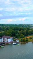 Approaching the beautiful multi-storied buildings on the river bank. Lots of green trees at backdrop. Top view. Vertical video