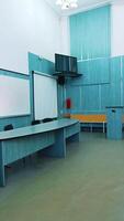 Modern interior of lecture hall. White board and presidium table in the university classroom. Empty auditorium with new equipment. Vertical video