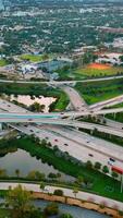 Road interchange of highways and freeways in colorful Miami. City scenery with lively traffic from top view. Vertical video