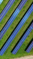 Contemporary solar energy farm. Rows of blue sunny batteries located on green field. Innovative collectors of clean sunny energy. Top aerial view. Orbital view. Vertical video