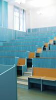 Modern auditorium with wooden desks without people. Large meeting hall with empty desks. Nobody in lecture hall in the university during quarantine. Vertical video