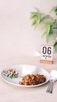 chicken curry with rice and salad on white plate with fork and knife photo