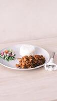 a plate with rice, chicken and salad on a wooden table photo