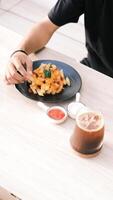 a person eating food on a table with a drink photo