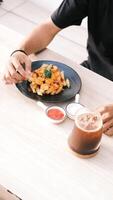 a person eating fries and a drink on a table photo