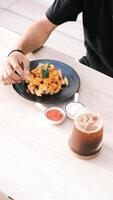 a person eating fries on a plate with a cup of coffee photo