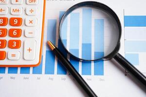 Eyeglass with calculator on chart graph paper. Finance, account, statistic, investment data economy, stock exchange b photo