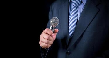 Man in business suit holding a microphone conducting a business interview, journalist reporting, public speaking, press conference, MC, Public speaking and giving speech in suit photo