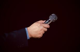 Man in business suit holding a microphone conducting a business interview, journalist reporting, public speaking, press conference, MC, Public speaking and giving speech in suit for audience concept. photo