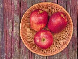 Three red apples in a wicker basket on a wooden table video