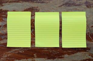 Three yellow striped notepads on a wooden background. Blank yellow notepads on an old wooden background. photo