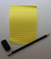 Yellow sticky notes, pencil and eraser on white background. photo