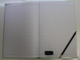 Blank notebook with pencil and eraser on white table photo