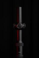 A sophisticated black scope with red details, featuring adjustable knobs and clear magnification indicators, isolated on a dark background. photo