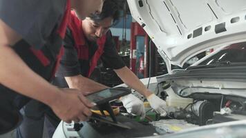 EV car check, mechanic workers coworker inspects and maintains service of electric engine and battery by application in auto garage station, professional technology transportation industry business. video