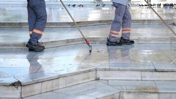 Workers clean large public plaza with mops in early morning light video