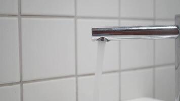 Water flowing from a chrome faucet in a clean bathroom setting video