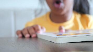 Child reading a colorful book at a table in a cozy indoor space video